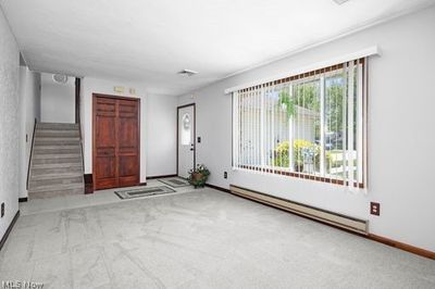 Carpeted foyer featuring a baseboard heating unit | Image 3