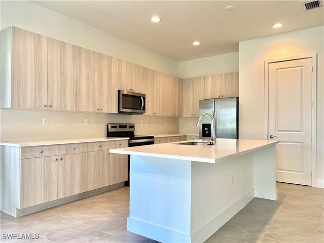 Kitchen featuring light brown cabinets, stainless steel appliances, and a center island with sink | Image 9
