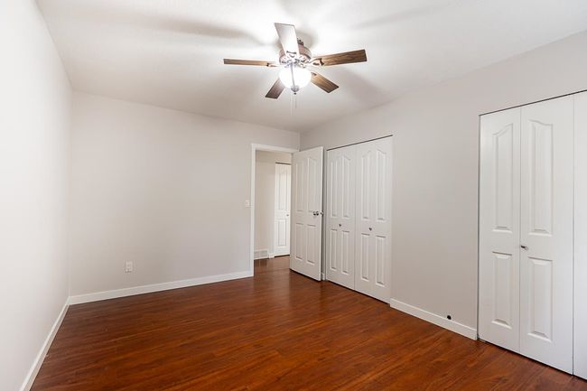 Unfurnished bedroom with two closets, dark wood-type flooring, and ceiling fan | Image 14