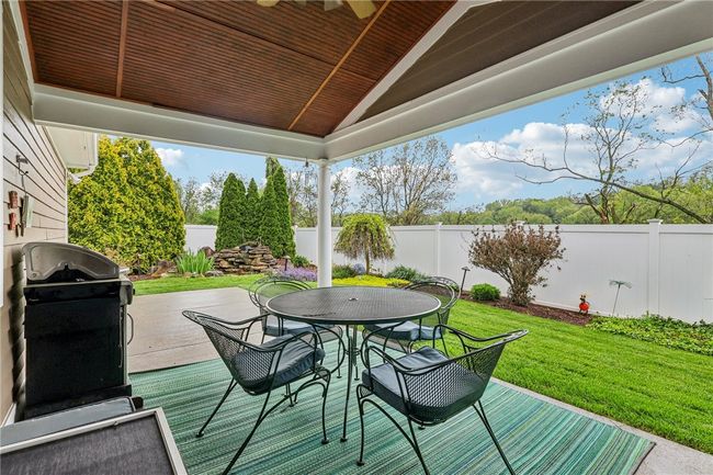 Covered Patio Overlooking a Fenced-in Manicured Back Yard with Small Pond and Waterfall | Image 46