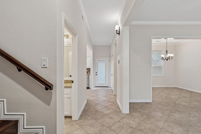 Hallway with crown molding, a chandelier, and light tile patterned floors | Image 7