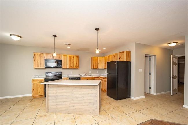 Kitchen with a sink, black appliances, light tile patterned floors, and light countertops | Image 10