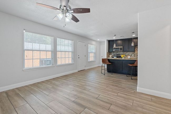 Kitchen featuring appliances with stainless steel finishes, a breakfast bar, light wood finished floors, backsplash, and ceiling fan | Image 28