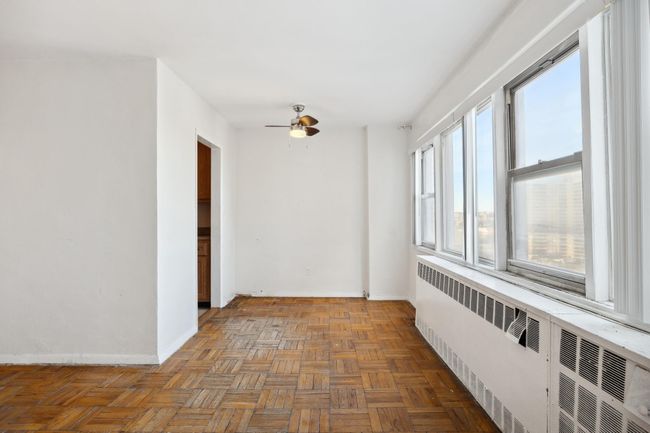 Empty room with ceiling fan, baseboards, and radiator | Image 7