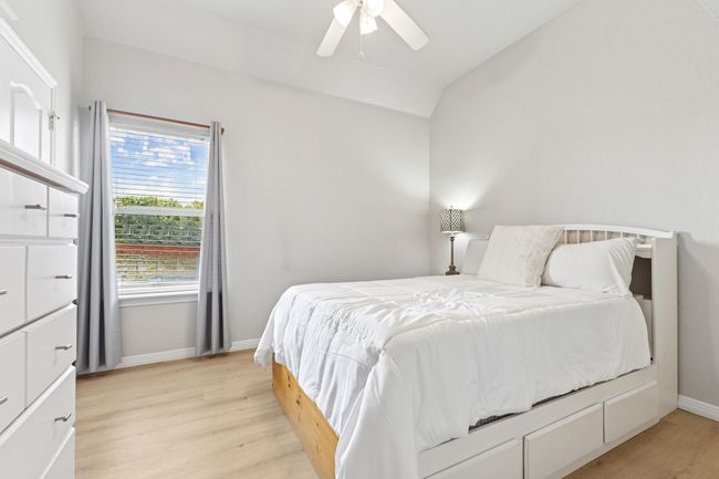 Bedroom with light wood-type flooring, vaulted ceiling, baseboards, and a ceiling fan | Image 27