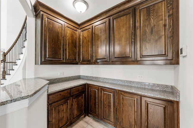 Kitchen with dark brown cabinetry and light stone countertops | Image 18