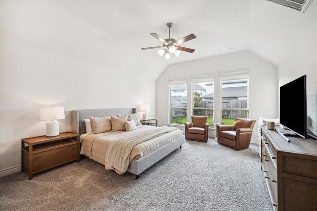 The primary suite offers a serene retreat, showcasing a coffered ceiling, an elegant ceiling fan and expansive windows that flood the spacious, luminous room with natural light. | Image 17