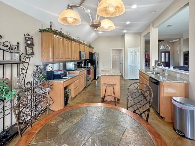 Kitchen with stainless steel appliances, a sink, a kitchen island, light stone counters, and lofted ceiling | Image 25