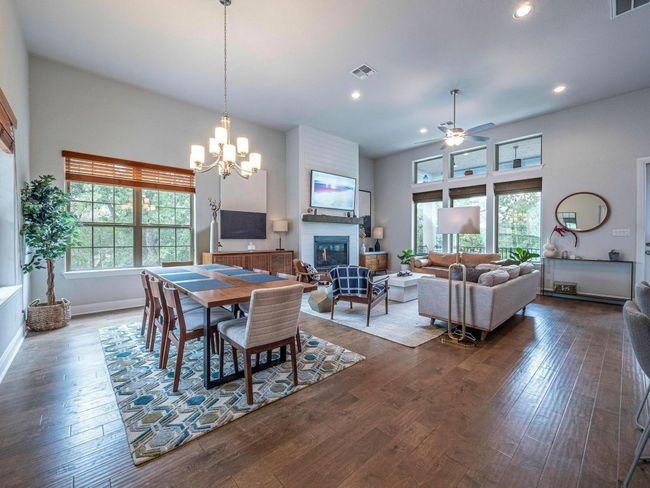 Dining room featuring ceiling fan, a glass covered fireplace, dark wood-type flooring, a chandelier, and recessed lighting | Image 6