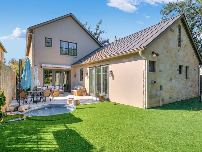 Rear view of property with a standing seam roof, stucco siding, a patio, metal roof, and stone siding | Image 23