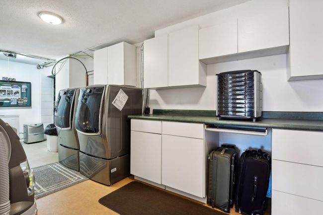 Finished laundry room has upscale washer and dryer with pedestal bases for storage. Large folding counter and plenty of cabinet storage. Laundry sink too. You will be impressed with the amount of storage available throughout this home. | Image 29