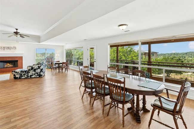 Dining room featuring wood finished floors, a tiled fireplace, ceiling fan, and crown molding | Image 8