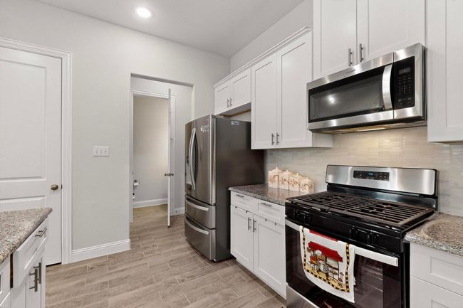 Kitchen with appliances with stainless steel finishes, light wood-style flooring, tasteful backsplash, white cabinets, and recessed lighting | Image 12