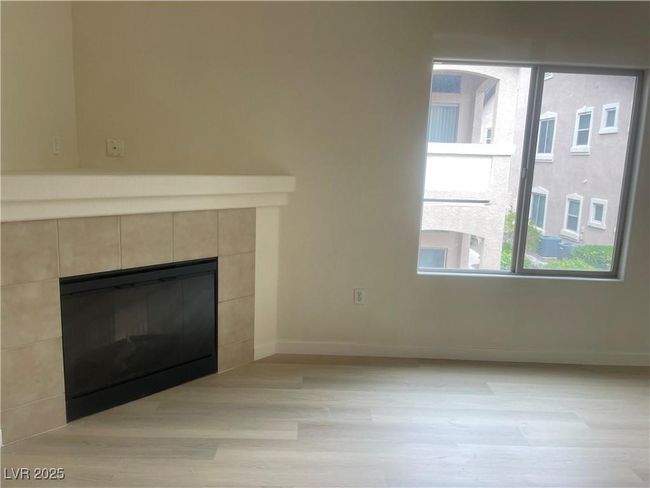 Unfurnished living room featuring a tile fireplace and light wood-style floors | Image 9