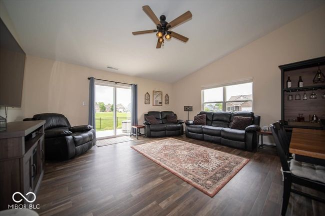 living area with ceiling fan, dark vinyl flooring with wood appearance and vaulted ceiling | Image 9