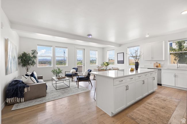 Kitchen featuring light wood-type flooring, a kitchen island, white cabinetry, and open floor plan | Image 9