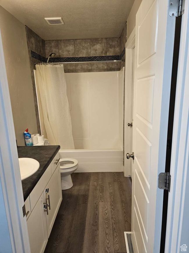 Bathroom featuring toilet, a textured ceiling, wood finished floors, and vanity | Image 13