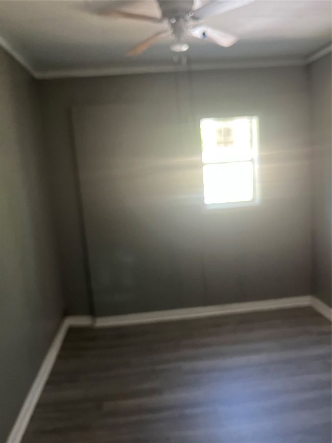 Empty room with crown molding, baseboards, a ceiling fan, and dark wood-style floors | Image 15