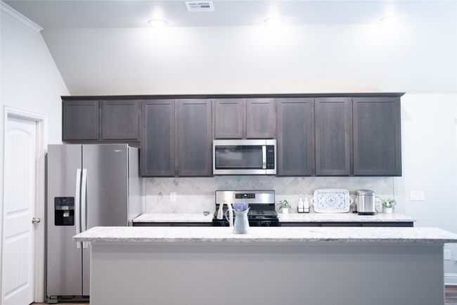 Kitchen with appliances with stainless steel finishes, visible vents, dark brown cabinets, and backsplash | Image 10