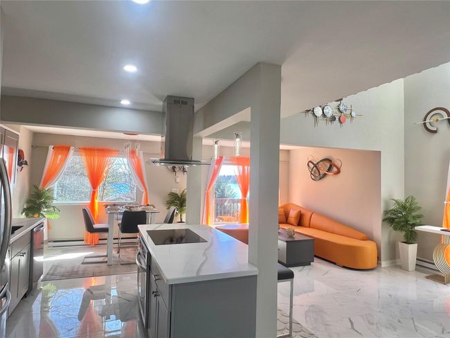 Kitchen featuring gray cabinets, black electric stovetop, island range hood, stainless steel dishwasher, and marble finish floor | Image 24
