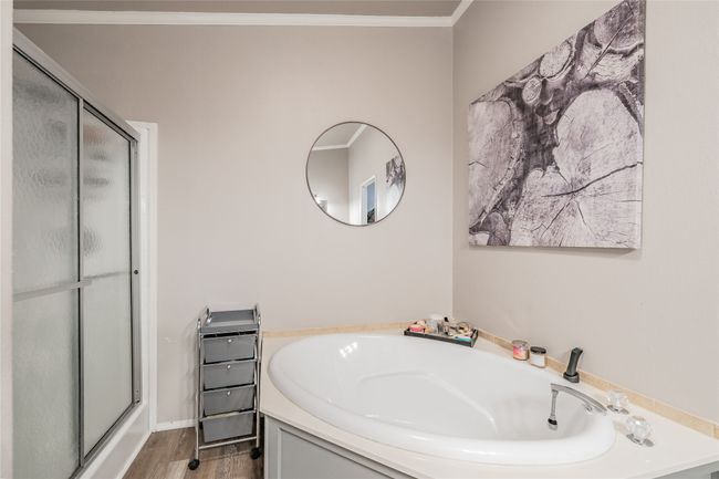 Bathroom featuring a shower stall, a bath, ornamental molding, and wood finished floors | Image 21