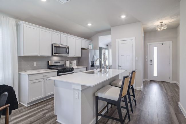 Kitchen featuring stainless steel appliances with and a breakfast bar, open to living area | Image 9