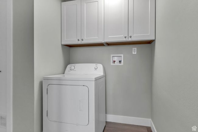 Laundry room featuring wood finished floors, washer / dryer, cabinet space, and baseboards | Image 23