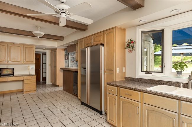 Kitchen with beam ceiling, stainless steel refrigerator with ice dispenser, light tile floors, and ceiling fan | Image 24