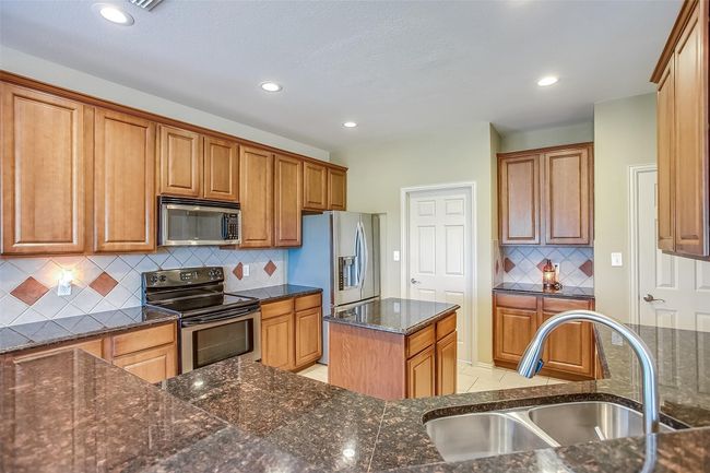 Kitchen featuring appliances with stainless steel finishes, tasteful backsplash and granite counters. | Image 11