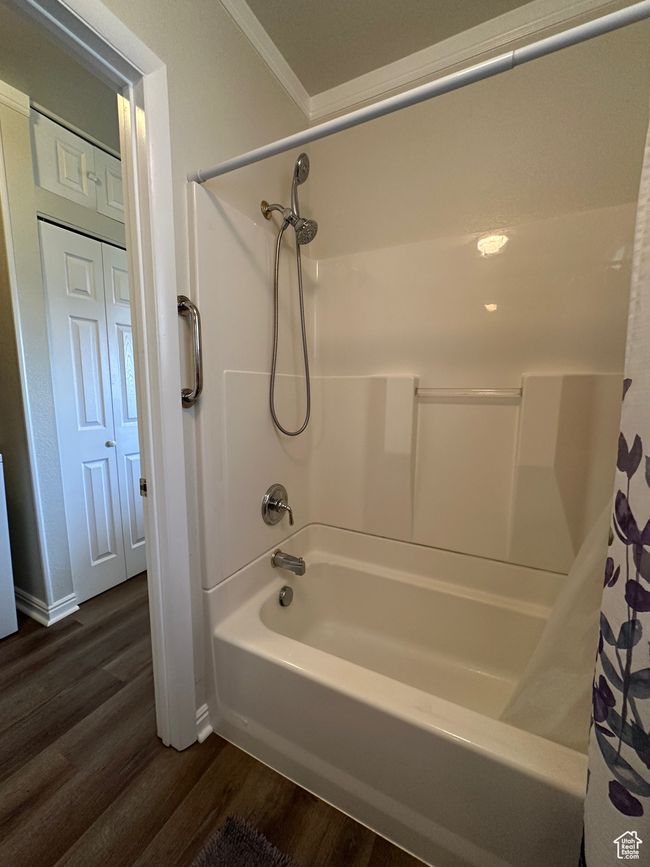 Full bath featuring wood finished floors, shower / bath combo with shower curtain, and crown molding | Image 18