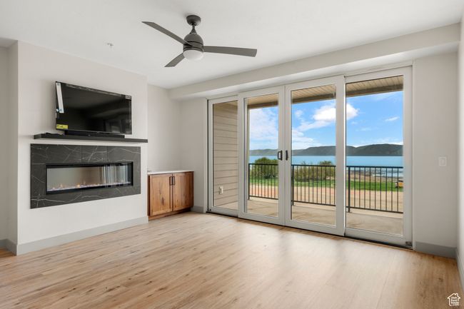 Unfurnished living room with light wood-style flooring, a high end fireplace, ceiling fan, and baseboards | Image 10