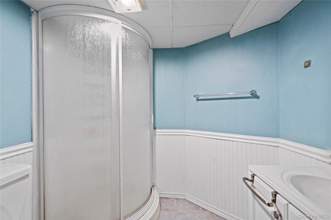 Full bathroom featuring wainscoting, vanity, a shower stall, and light tile patterned flooring | Image 19