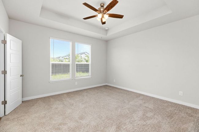 Spare room featuring a ceiling fan, a tray ceiling, carpet flooring, and baseboards | Image 21