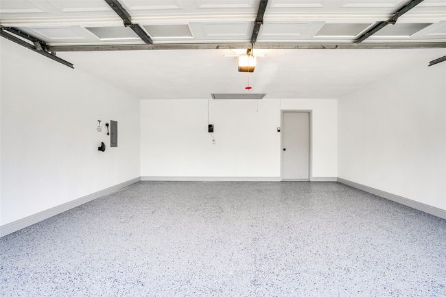 Garage with baseboards, a garage door opener, and electric panel | Image 29