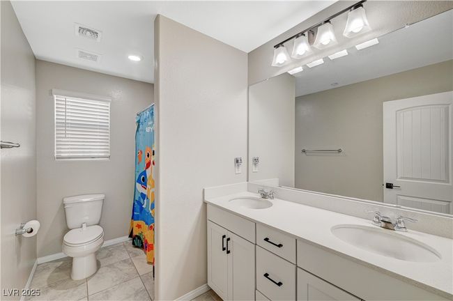 Bathroom with toilet, baseboards, double vanity, and a shower with shower curtain | Image 45