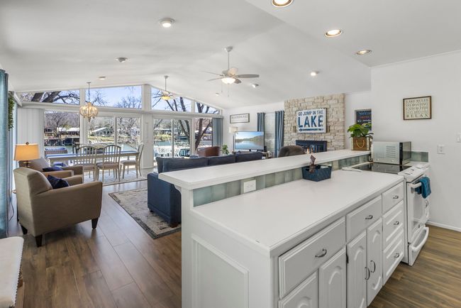 Kitchen featuring white cabinetry, a peninsula, open floor plan, and vaulted ceiling | Image 4