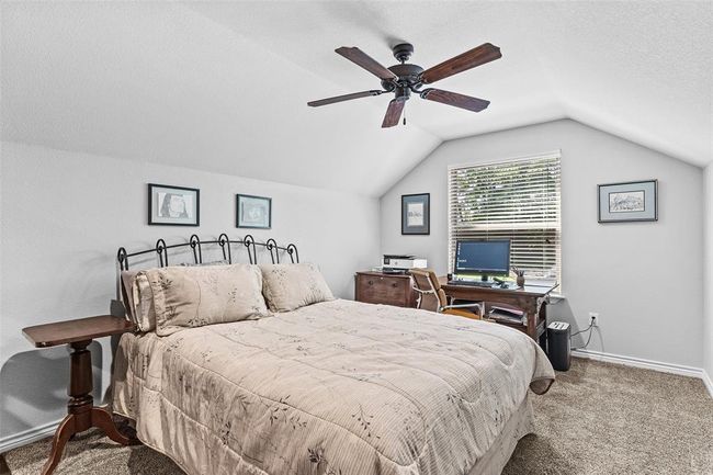 Carpeted bedroom featuring a textured ceiling, ceiling fan, and vaulted ceiling | Image 17