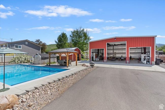 View of swimming pool featuring a gazebo, an outdoor structure, and an outbuilding | Image 13