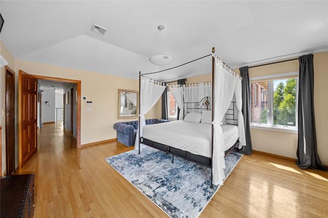Bedroom featuring baseboards, visible vents, light wood-style flooring, and lofted ceiling | Image 10