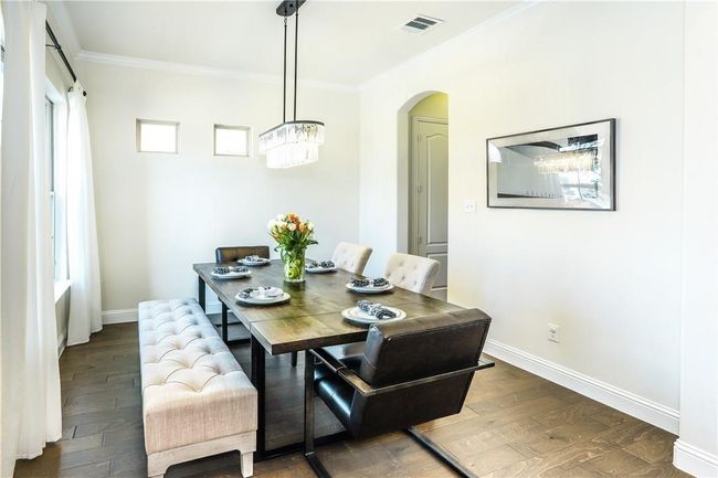 Dining room featuring crown molding, a chandelier, wood finished floors, and arched walkways | Image 4