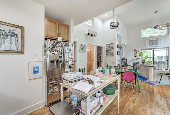 Kitchen featuring light wood-style flooring, a towering ceiling, ceiling fan, stainless steel fridge with ice dispenser, and a wall mounted AC | Image 39