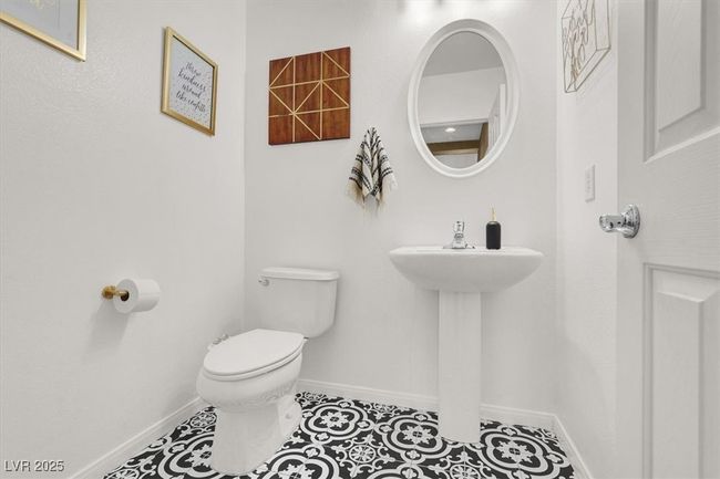 Half bathroom featuring toilet, baseboards, a sink, and tile patterned flooring | Image 11