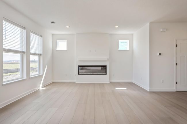Photo is of the actual home. The spacious family gathering area seamlessly connects to the kitchen area, perfect for entertaining. It also features many large windows providing warm natural light and a fireplace. | Image 6
