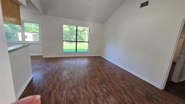 Unfurnished living room with lofted ceiling, plenty of natural light, and dark wood finished floors | Image 4