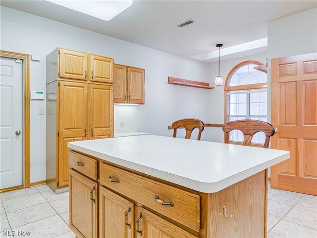 Kitchen featuring pendant lighting, light countertops, brown cabinets, and light tile floors | Image 16