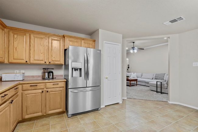 Kitchen featuring a ceiling fan, baseboards, visible vents, light countertops, and stainless steel fridge with ice dispenser | Image 18