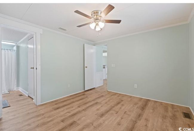 Bedroom with light wood-type flooring, ornamental molding, baseboards, and ceiling fan | Image 19
