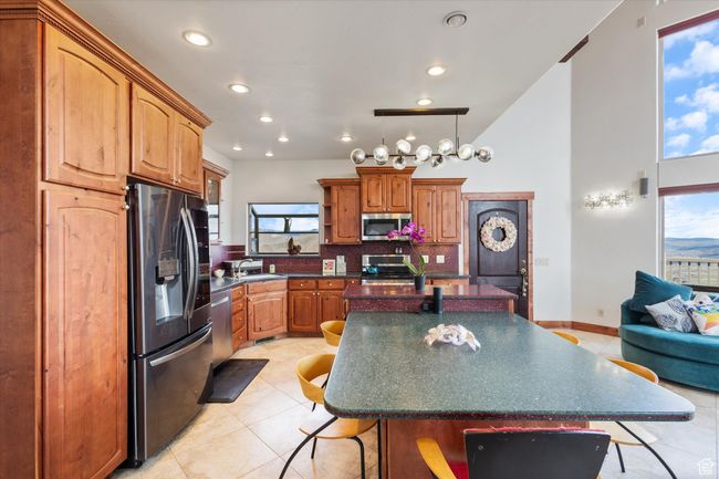 Kitchen featuring dark countertops, a sink, a breakfast bar, stainless steel appliances, and a kitchen island | Image 7