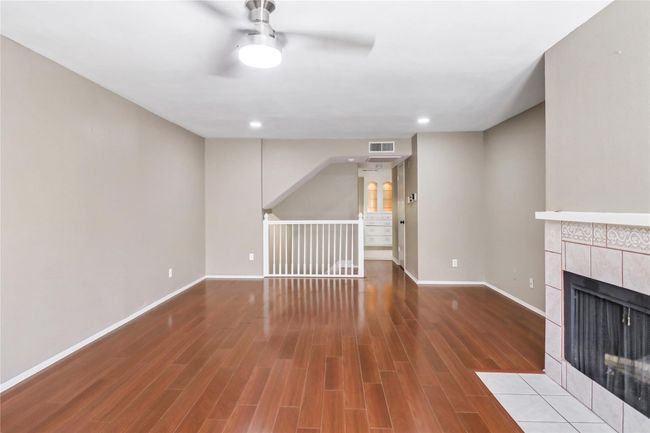 Unfurnished living room with ceiling fan, a fireplace, baseboards, wood finished floors, and recessed lighting | Image 10