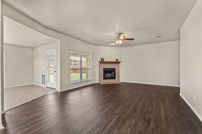 Unfurnished living room featuring a ceiling fan, dark wood finished floors, and a fireplace | Image 16